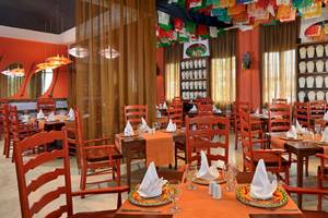 Innenansicht des Restaurants im Paradisus Varadero Resort & Spa mit orangefarbenen Tischen und Stühlen.