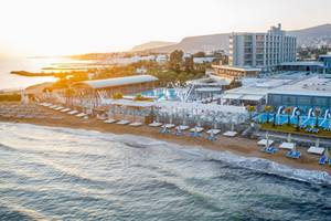 Aerial view of Arina Beach Resort with swimming pools and beach loungers at sunset.