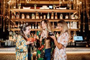Drei Frauen, die Cocktails in der Bar des Hilton Dubai Palm Jumeirah halten.