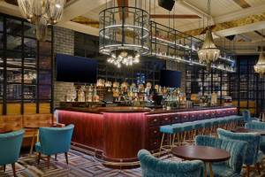 Innenansicht der Bar im Hilton Dubai Palm Jumeirah mit Holztheke und blauen Stühlen.
