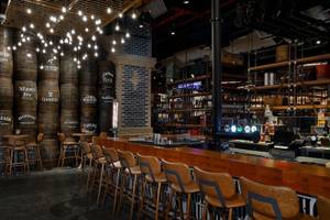 Innenansicht der Bar im Hilton Dubai Palm Jumeirah Hotel mit Barhockern, Theken und Flaschen.