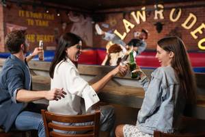 Besucher sitzen an der Bar des Hilton Dubai Palm Jumeirah und lachen.