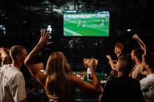 Gruppe von Leuten, die Fußball in der Bar des Hilton Dubai Palm Jumeirah anschauen, eine Person hebt die Fäuste
