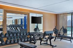Fitnesscenter im Hilton Dubai Palm Jumeirah mit Laufbändern, Hanteln und einer Fernsehwand