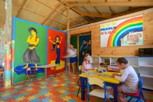 Kinder Spielzimmer mit bunten Wandmalereien und einem Puzzletisch.