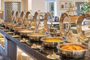 Buffettisch im Sealine Beach, A Murwab Resort mit verschiedenen Speisen in Silberschalen.