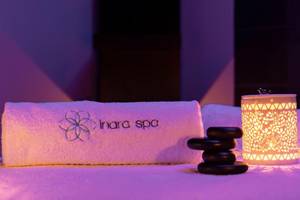 Ein Handtuch und ein Becher mit Steinen im Inara Spa bei Nacht