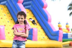 Mädchen steht lächelnd vor einem aufblasbaren Spielplatz