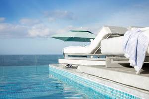 Außenpool des Mare Paphos Hotels mit Lounge-Sesseln und Blick aufs Meer.
