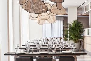 Foto des Mare Paphos Hotels Innenbereichs mit eingerichteten Tischen und Stühlen sowie einer großen Deckenlampe.