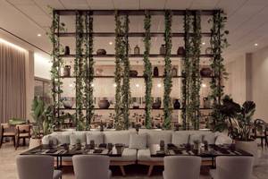 Inneneinrichtung des Mare Paphos Hotels, Restaurantbereich mit grünen Pflanzen und Holztischen.