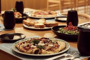 Foto von mehreren Gerichten auf einem Tisch im Mare Paphos Hotel, darunter Pizza, Salat und Getränke.