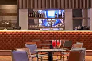 Innenansicht der Bar im Mare Paphos Hotel mit Cocktails und braunen Lederstühlen.
