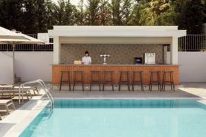Poolbar des Mare Paphos Hotels mit einer Bedienung und Sonnenschirm.