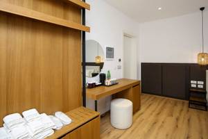 Innenansicht eines eleganten Hotelzimmers mit Holzboden und Möbeln, einem Schreibtisch und einem großen Spiegel.