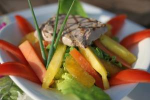 Salat mit verschiedenen Früchten, Gemüse und Fleisch auf einem weißen Teller.