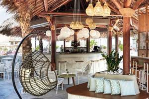 Loungebereich des Atlantica Caldera Palace Hotels mit Hängesessel, Tischen und Bar.