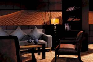 Interieur des Hotellobbys im Traders Hotel Qaryat Al Beri mit Sofa, Teekannen und Bücherregal.