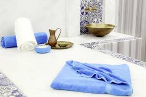 Spa-Bereich im Lemon & Soul Garden Makadi mit weißen und blauen Handtüchern, einem goldenen Becken und anderen Spa-Utensilien.