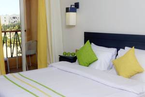 Bett im Zimmer des Lemon & Soul Garden Makadi Hotels mit grünen und gelben Kissen.