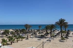 Strandaussicht des Paradis Palace Hotels mit vielen Sonnenschirmen und einem Volleyballnetz.