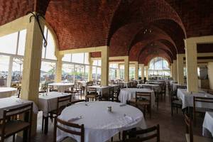 Innenansicht des Restaurants Paradis Palace mit gemauerten Decken und runden Bögen, gedeckten Tischen und Stühlen.