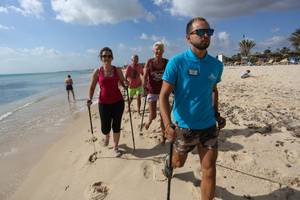 Gruppe von Gästen und ein Betreuer wandern am Strand des Paradis Palace Hotels