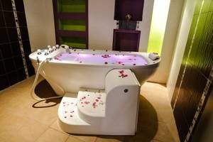Badezimmer im Paradis Palace mit einer Badewanne voller Rosenblättern und einem gefliesten Boden.