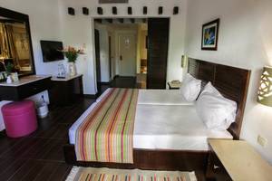 Innenansicht eines Doppelzimmers im Paradis Palace Hotel mit zwei Betten, Tisch, Fernseher und Dekor.