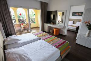 Innenansicht eines Doppelzimmers im Paradis Palace Hotel mit zwei Betten, Balkon und Wohnzimmer