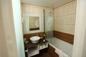 Badezimmer im Paradis Palace Hotel mit Badewanne, Waschbecken und Spiegel.