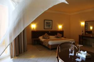 Ein elegantes Hotelzimmer im Nour Palace Resort & Thalasso mit einem Bett, einem Schreibtisch und einem Fenster.