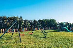 Kinderspielplatz im Hotel Iberostar Waves Averroes mit Schaukeln, Rutsche und buntem Zaun