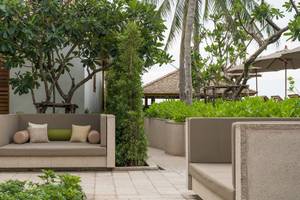 Gartenlounge im Banana Fan Sea Resort mit zwei Sofas, Kissen und Palmen im Hintergrund.