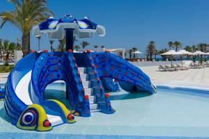 Wasserrutsche im Poolbereich des JAZ Tour Khalef Hotels mit bunten Farben und einem sommerlichen Hintergrund.