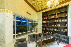 Hotellobby des JAZ Tour Khalef mit Sofas, einem Tisch, einem Bücherregal und einer großen Fensterfront.