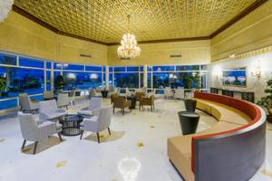 Lobby des JAZ Tour Khalef Hotels mit goldener Decke, Kronleuchter, Sofas und Tischen.