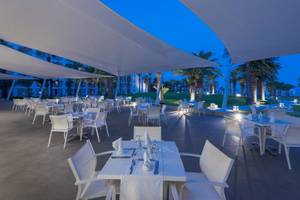 Außenbereich des JAZ Tour Khalef Hotels am Abend mit vielen weißen Tischen und Stühlen unter großen Markisen.