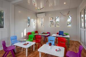 Farbige Kinderstühle und Tische im JAZ Tour Khalef Kinderzimmer, bunte Dekorationen an der Decke.
