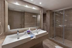 Badezimmer mit zwei Waschbecken, einem großen Spiegel und einer Glasdusche im JAZ Tour Khalef Hotel