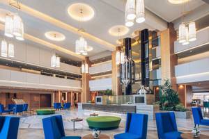 Das Foyer des Iberostar Selection Kuriat Palace Hotels mit blauen Stühlen, Tischen und Pflanzen.