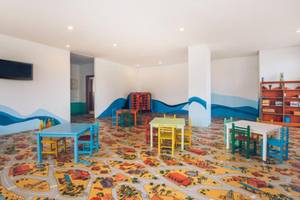 Kinderspielzimmer im Iberostar Selection Kantaoui Bay mit bunten Tischen, Stühlen und Wandmalerei.