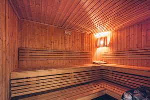 Eine Holzsauna im Iberostar Selection Diar El Andalous mit Holzbänken und einer Lampe an der Wand.