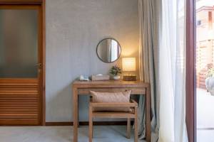 Ein schlichtes Hotelzimmer mit einem Schreibtisch, einer Lampe und einem Spiegel.