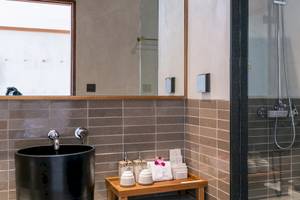 Badezimmer im Banana Fan Sea Resort mit einem schwarzen Waschbecken, einem Spiegel und einer Glasdusche.
