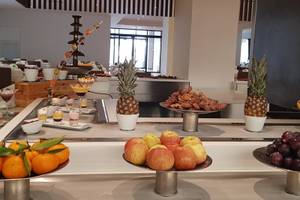 Buffet-Tisch im Orangers Garden Villas & Bungalows mit verschiedenen Früchten, Desserts und einer Schokoladenfontäne.