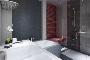 Badezimmer im Orangers Garden Villas & Bungalows mit einer weißen Badewanne, roten Fliesen und einer Glasdusche.