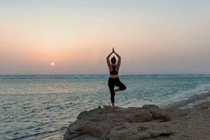 Frau macht Yoga am Strand des Mövenpick Resorts El Quseir.