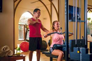 Ein Fitnesstrainer hilft einer Frau im Gym, die ein Trainingsgerät benutzt.