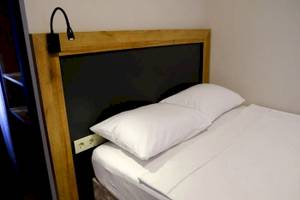 Bett im Club Wasa Holiday Village Hotel mit zwei weißen Kissen und Kopfteilbeleuchtung.